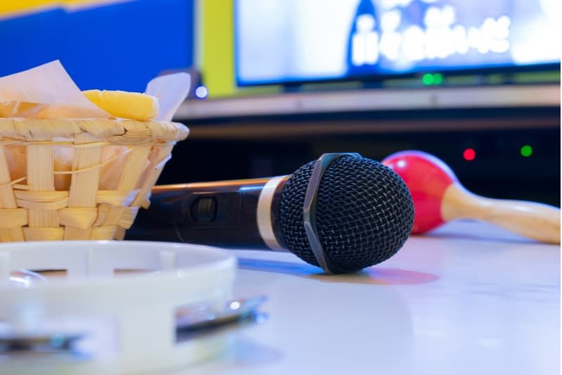 Mikrofon und Tamburin werden für eine Karaoke-Session auf den Tisch neben dem Fernseher gestellt