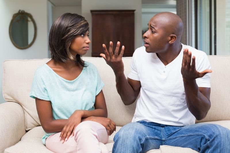 Mann und Frau streiten sich, während sie auf dem Sofa sitzen
