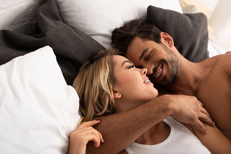 Schönes Paar, das sich im Bett umarmt und lächelt