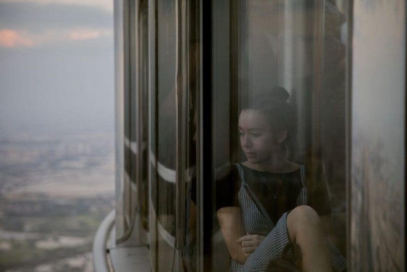 Traurige Frau im Wolkenkratzer, die durch das Fenster schaut