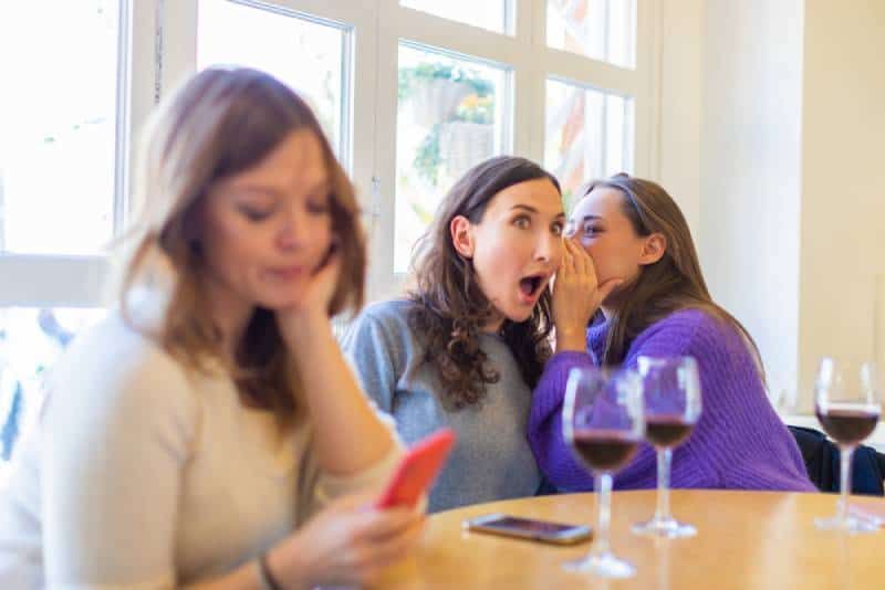 Zwei bösartige Mädchen tratschen im Café über ihre Freundin
