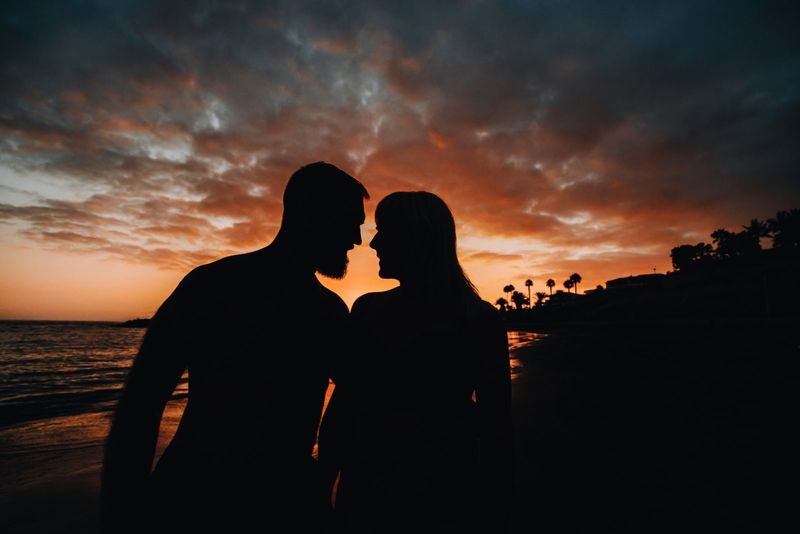 Romantisches Paar am Strand bei einem farbenfrohen Sonnenuntergang im Hintergrund