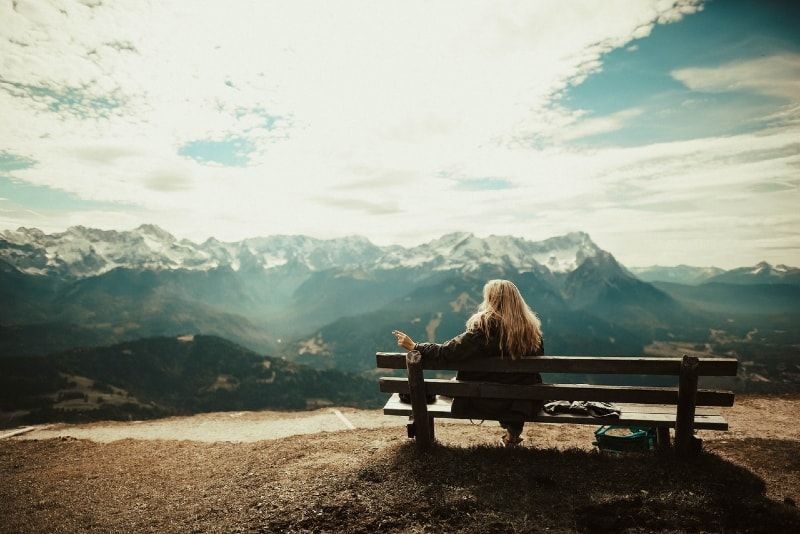 Frau sitzt auf einer Bank und blickt auf den Berg