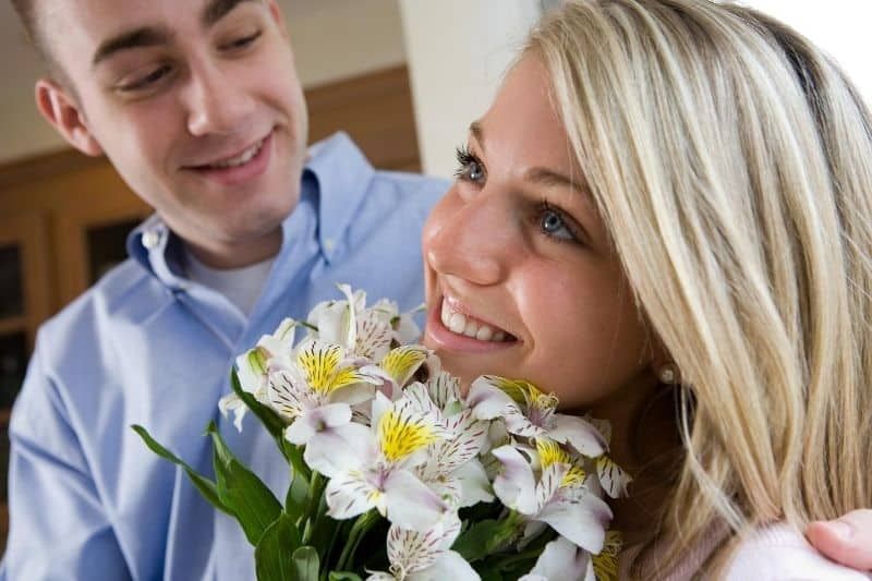 Mann schenkt einer Frau im Haus Blumen