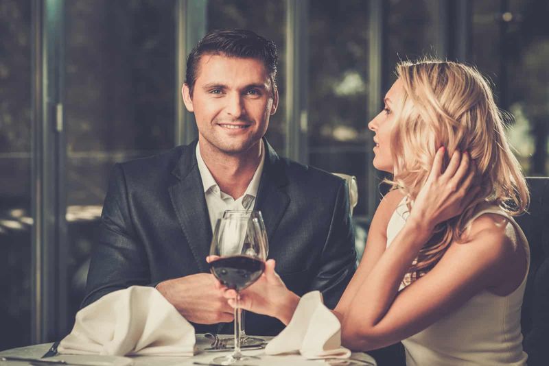 ein lächelnder Mann und eine lächelnde Frau, die Wein trinken