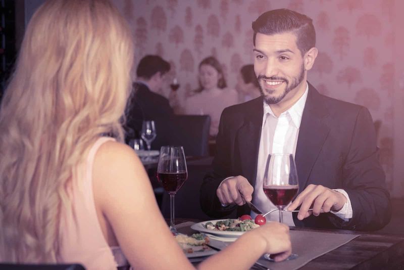 Ein lächelnder Mann sitzt mit einer Frau an einem Tisch und isst