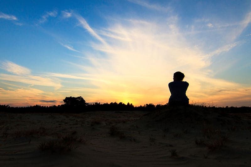 Silhouette einer Frau in Susnet, die in einem Nationalpark sitzt