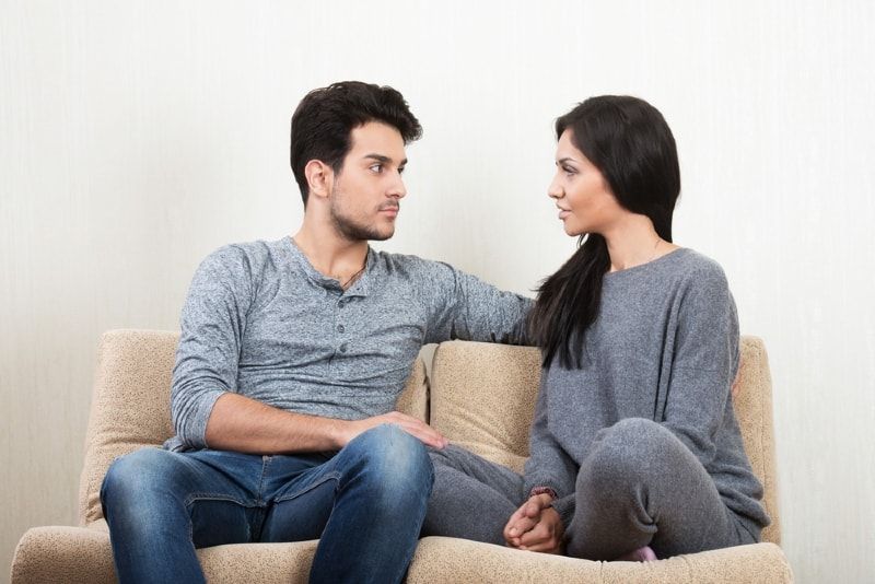 Mann und Frau unterhalten sich, während sie auf der Couch sitzen