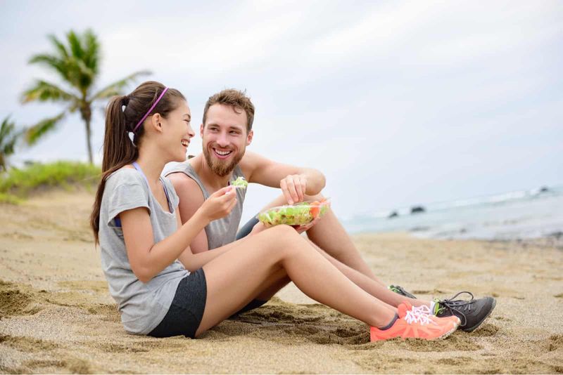Ein lächelnder Mann und eine lächelnde Frau sitzen am Strand und unterhalten sich