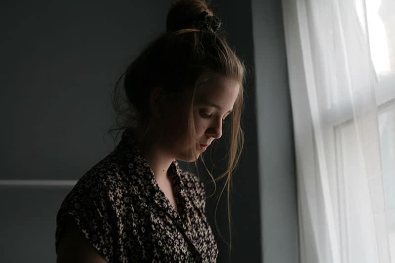 Traurige junge Frau, die allein im Raum steht
