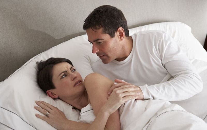 Paar hat Meinungsverschiedenheiten im Bett, Mann versucht sie zu berühren