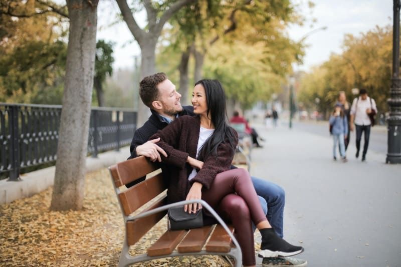 Mann und Frau sitzen auf einer Holzbank und lächeln
