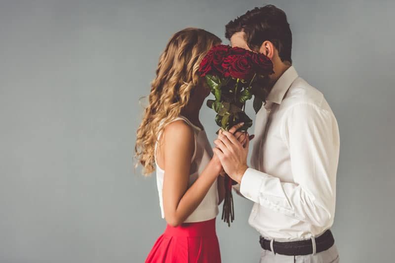 Ein Mann und eine Frau bedeckten ihre Gesichter mit einem Strauß Rosen