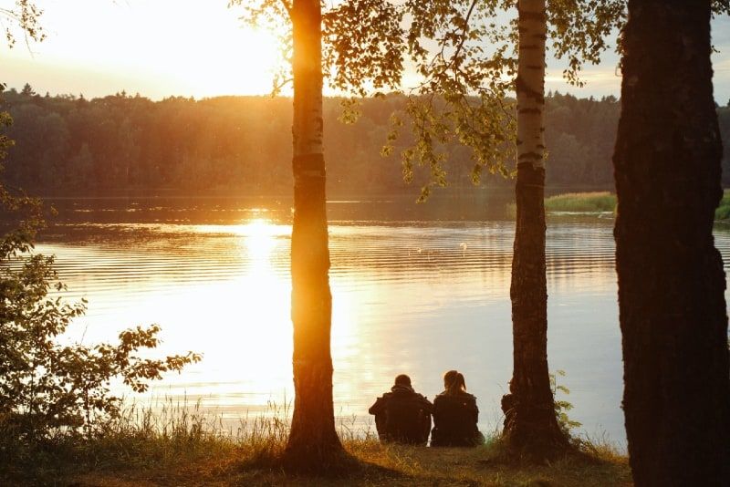 Mann und Frau sitzen bei Sonnenuntergang am Wasser
