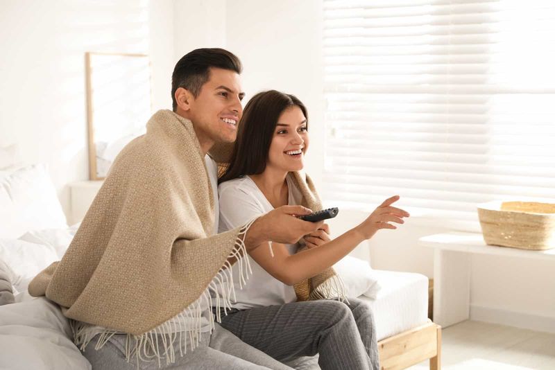 Ein lächelnder Mann und eine Frau sitzen auf der Couch und sehen fern