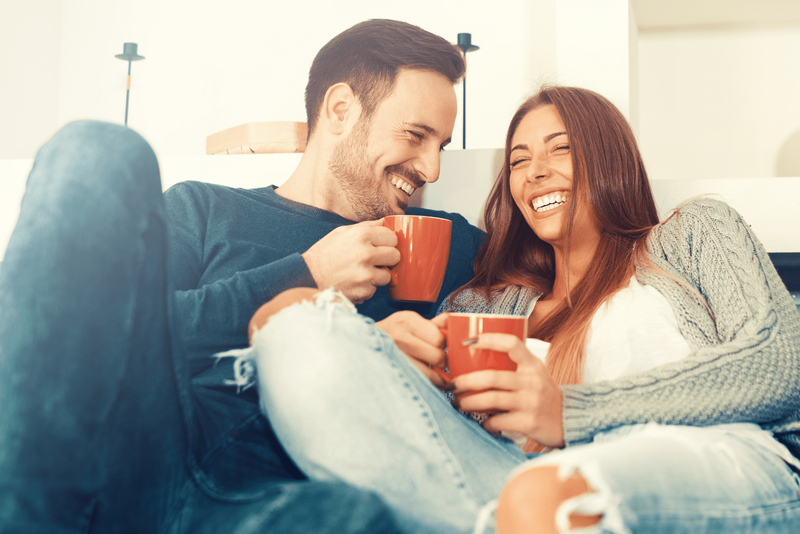Ein Mann und eine Frau sitzen, lachen und trinken Kaffee