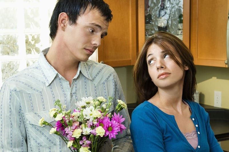 Mann schenkt einer Frau Blumen und bittet um Vergebung
