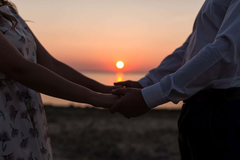 Händchen haltendes Paar mit Sonnenuntergang im Hintergrund
