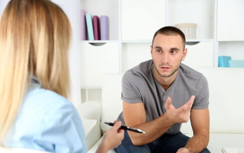 Mann spricht mit einer Psychologin, die vor ihr sitzt