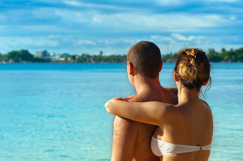 Rückansicht eines liebevollen Paares in Badebekleidung mit Blick auf das Meer