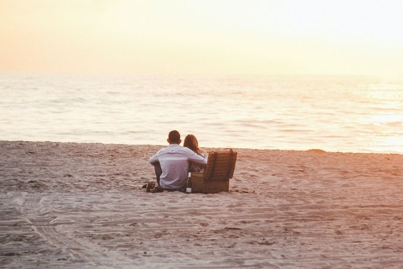 Mann und Frau sitzen am Strand und schauen aufs Meer