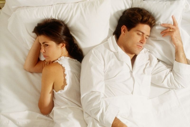Verärgertes Paar im Bett, liegend in ihren weißen Pyjamas