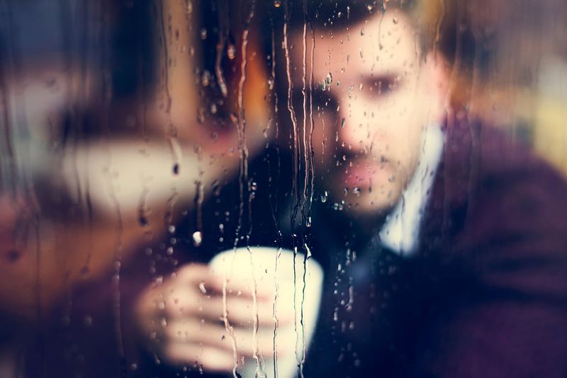 Ein Mann sitzt am Fenster und trinkt Kaffee