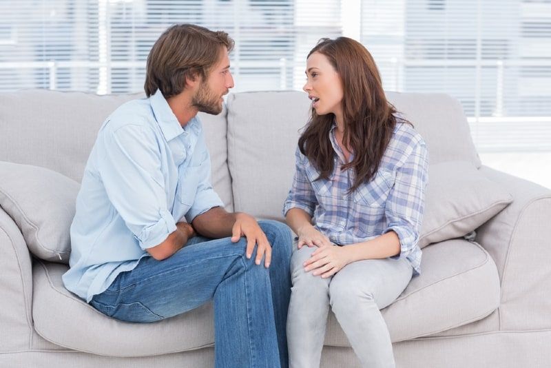 Mann und Frau unterhalten sich, während sie auf dem Sofa sitzen