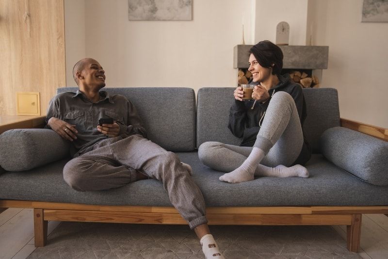 Mann mit Telefon und Frau sitzen auf der Couch und reden