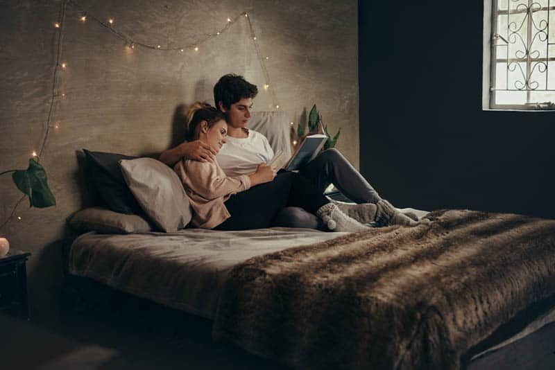Romantisches Paar liegt auf dem Bett und liest ein Buch