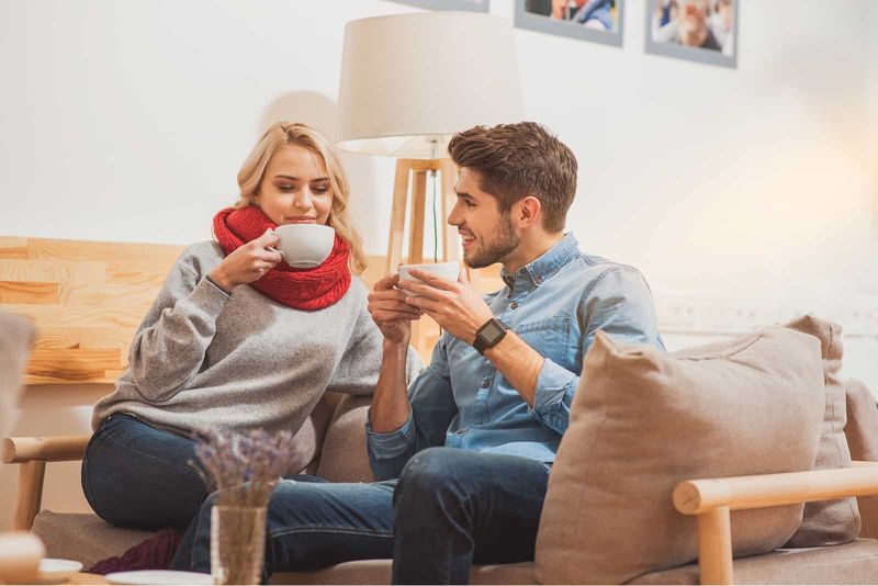 Ein Mann und eine Frau sitzen auf einer Couch und trinken Kaffee und unterhalten sich