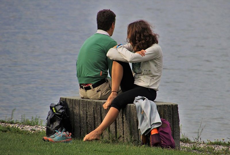 Mann und Frau sitzen tagsüber neben dem Gewässer