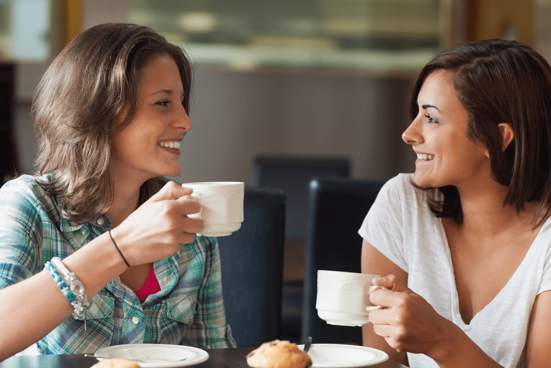 Zwei lächelnde Freunde sitzen beim Kaffee und reden