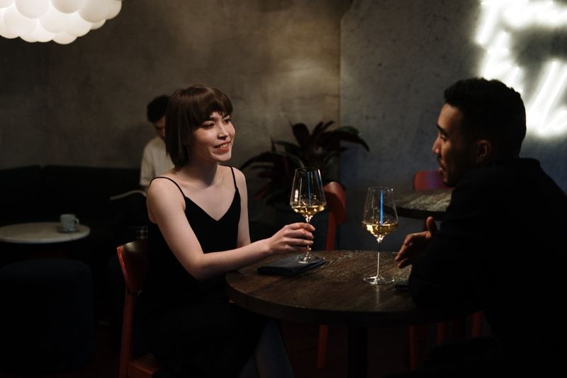 Mann und Frau trinken Wein, während sie am Tisch sitzen