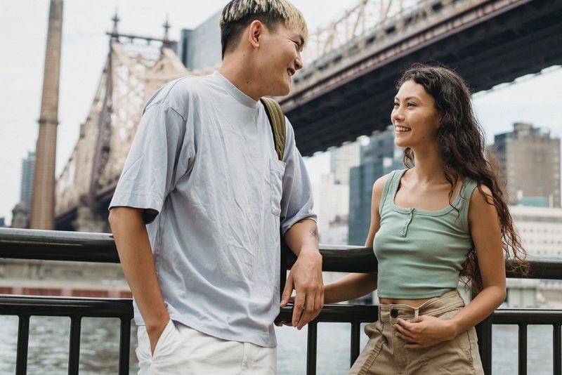 Mann und Frau lächeln, während sie in der Nähe der Brücke stehen