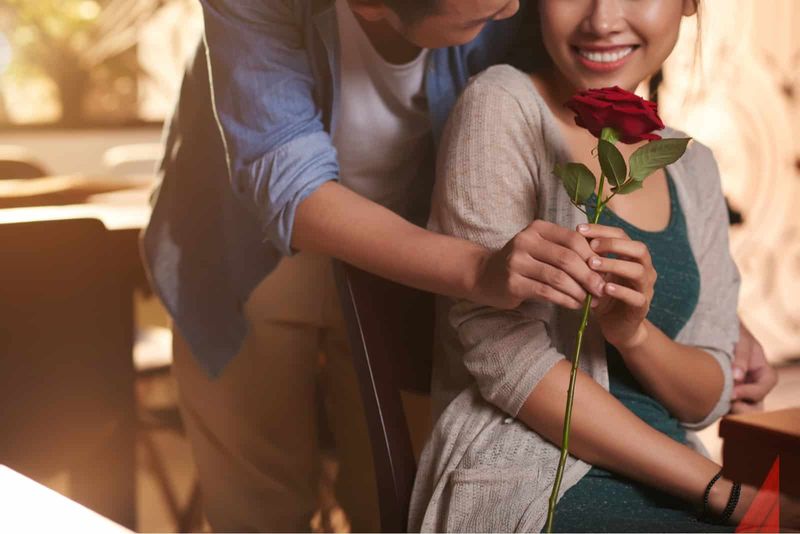 Mann schenkt einer glücklichen Frau eine rote Rose